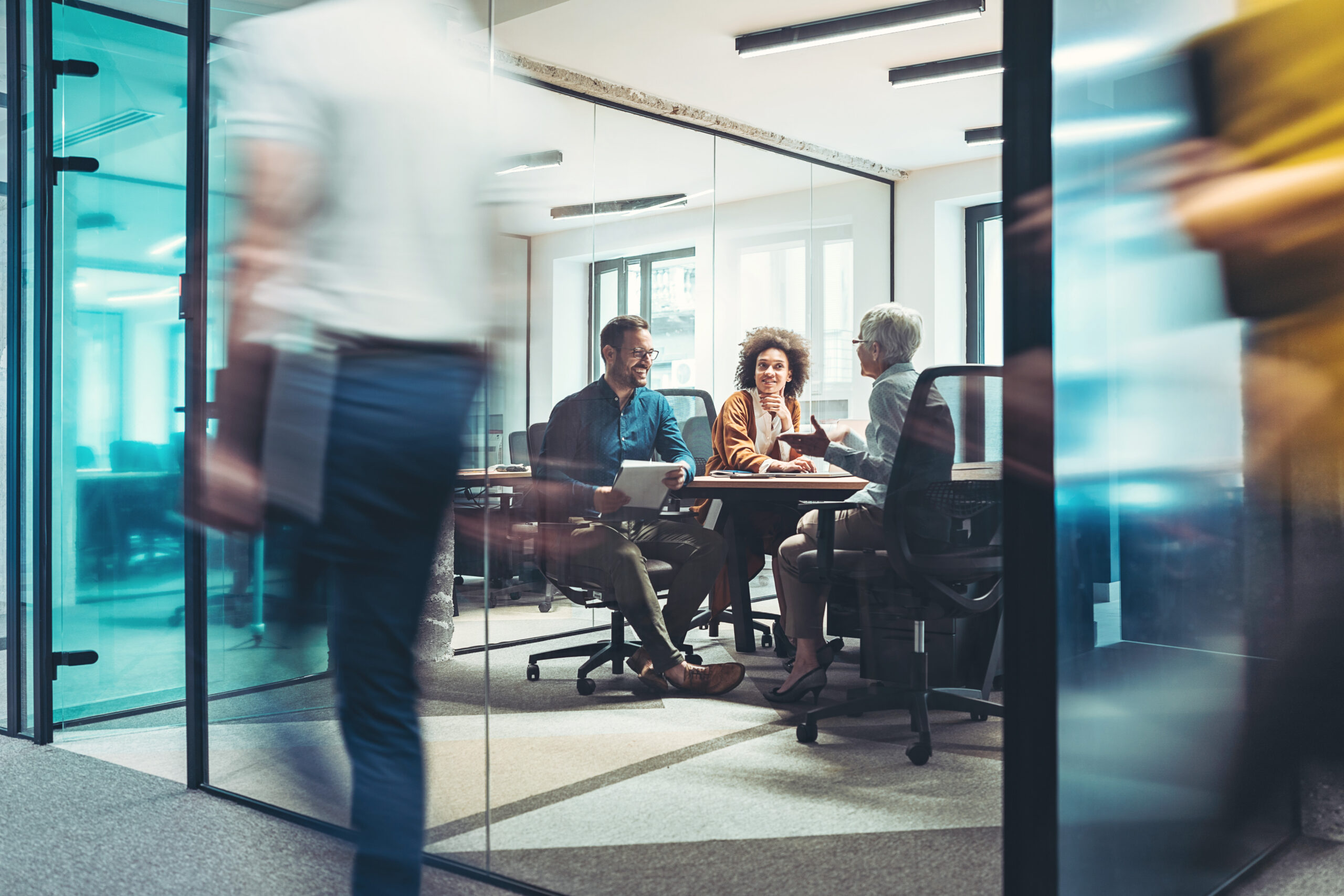 shot of team meeting in boardroom through glass doors.
